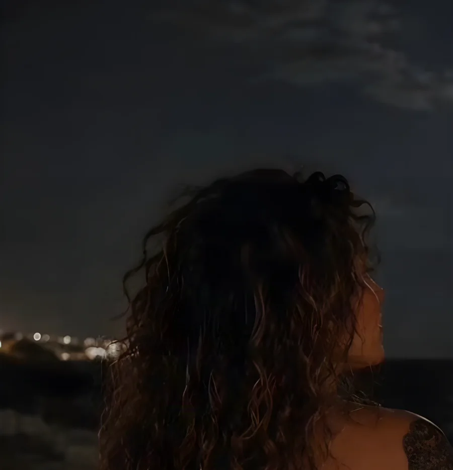 Noelia, de espaldas, frente al mar de noche